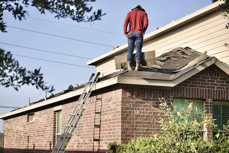 Professional roofer working on a residential roof in Matinecock